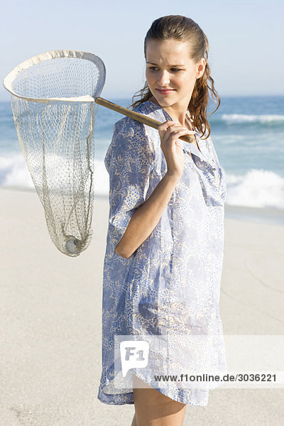 Woman carrying a fishing net on the beach