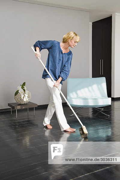 Frau reinigt den Boden mit einem Wischmopp