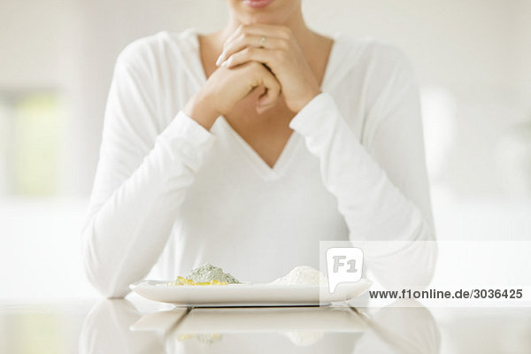 Frau sitzt an einem Tisch mit Tonen auf einem Teller