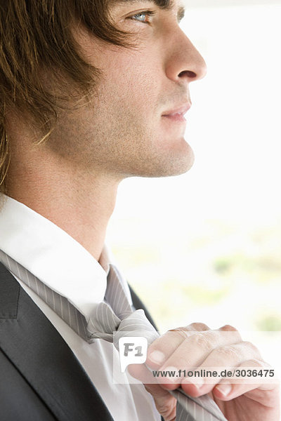 Close-up of a groom adjusting his tie