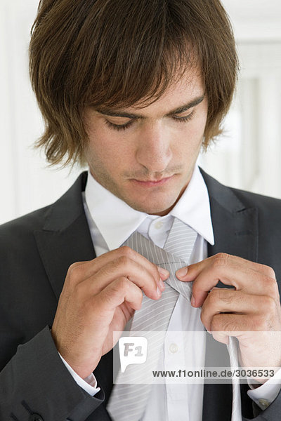 Nahaufnahme eines Bräutigams  der seine Krawatte anpasst.