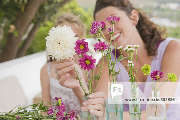 Frau mit ihrer Tochter  die Blumen in einer Vase arrangiert.