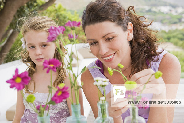 Frau mit ihrer Tochter  die Blumen in einer Vase arrangiert.