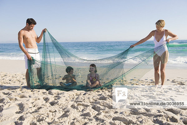 Familienspiel mit einem Fischernetz am Strand