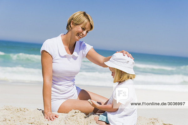 Woman sitting with her daughter on the beach