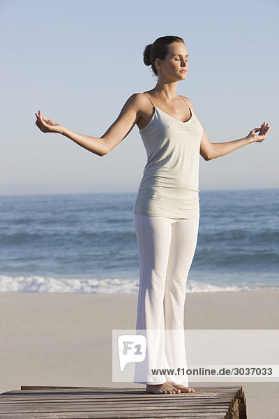 Frau praktiziert Yoga auf einer Strandpromenade