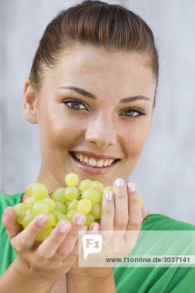 Frau hält Weintrauben und lächelt