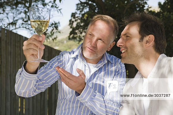 Zwei Freunde beim Betrachten eines Weinglases