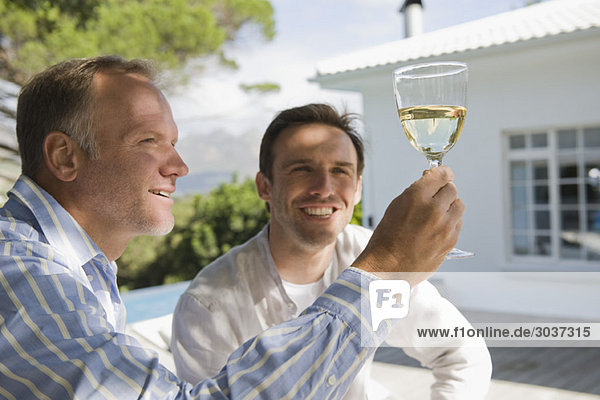 Zwei Freunde beim Betrachten eines Weinglases