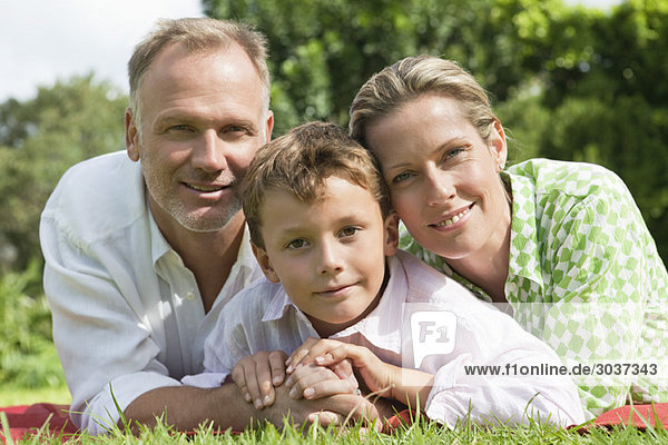 Junge mit seinen Eltern im Park auf Gras liegend