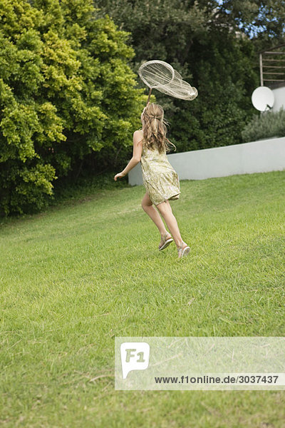 Mädchen beim Spielen mit einem Schmetterlingsnetz im Garten