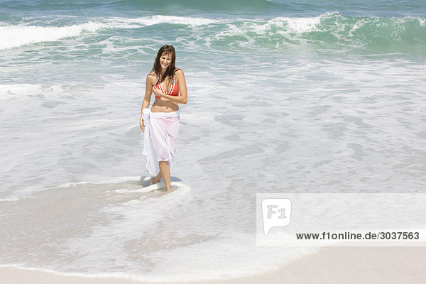 Frau geht am Strand spazieren und lächelt