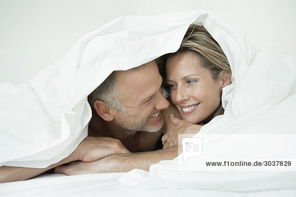 Paar in Bettdecke gewickelt