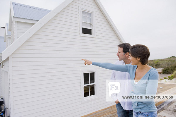 Woman pointing towards a house with a man standing beside her