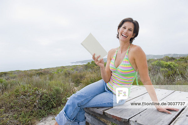 Woman sitting on a boardwalk and reading a book