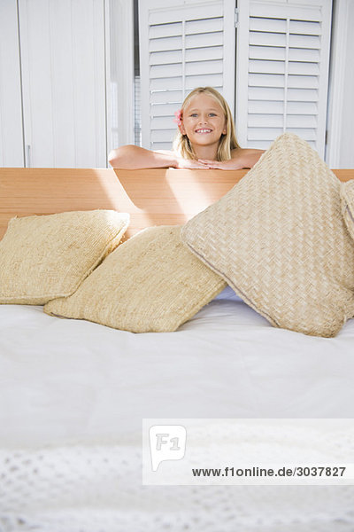 Porträt eines Mädchens  das sich auf ein Bett lehnt und lächelt