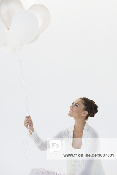 Frau hält Luftballons und lächelt