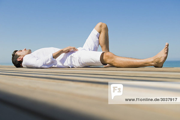 Mann auf einer Strandpromenade am Strand liegend
