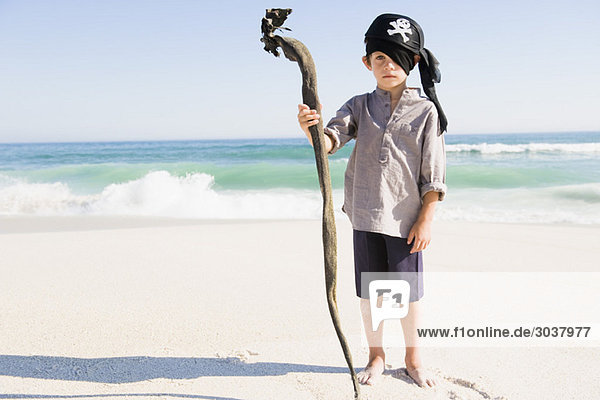 Junge in Piratenkostüm am Strand stehend