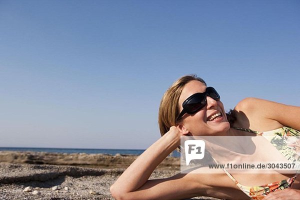 Frau mit Sonnenbrille entspannt am Strand