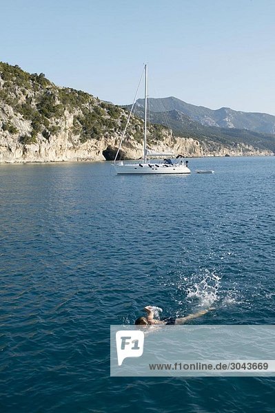Woman swimming with boat in background