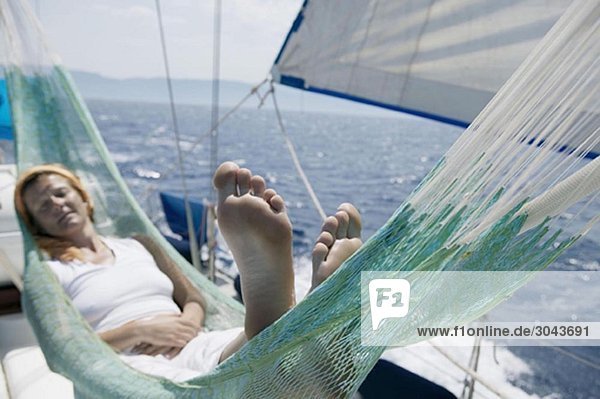 Woman lying in hammock on sailing boat