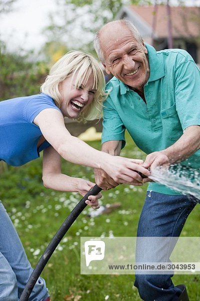 woman and old man playing with hose
