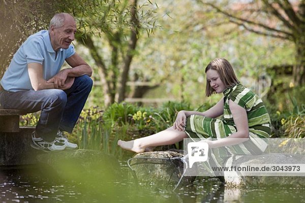 old man and young girl at pond