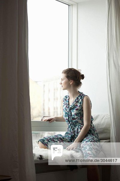 Frau die aus dem Fenster schaut.
