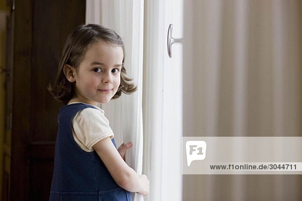 young girl standing at curtains