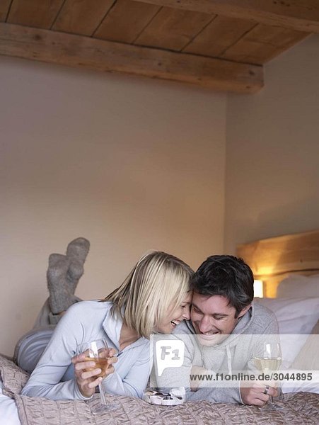 Frau und Mann lächelnd auf dem Bett liegend