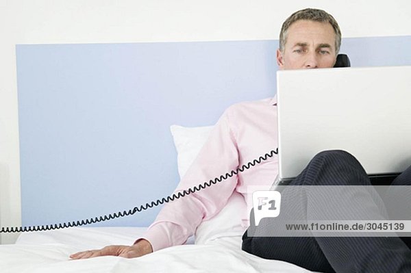 Geschäftsmann der in seinem Hotelzimmer arbeitet.
