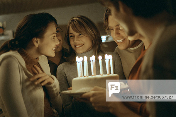 Geburtstagskuchen mit angezündeten Kerzen für die junge Frau