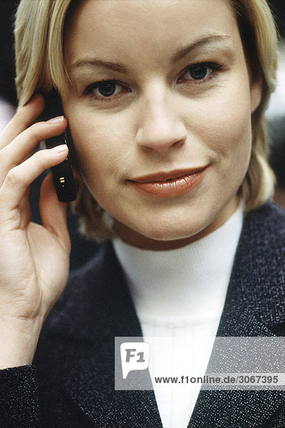 Frau telefoniert mit dem Handy und schaut optimistisch in die Kamera Portrait