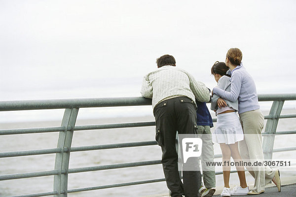 Familie zusammen am Seewandgeländer mit Blick auf die Aussicht