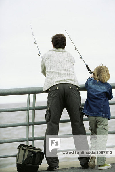 Vater und Sohn fischen vom Pier aus  Rückansicht