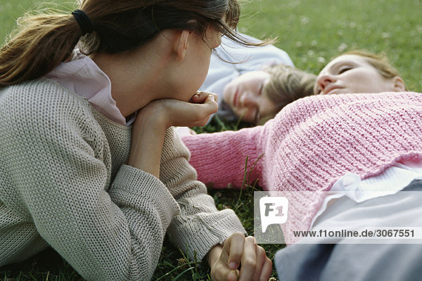 Mädchen kontemplativ beobachtende Mutter und Bruder liegend  auf Gras liegend