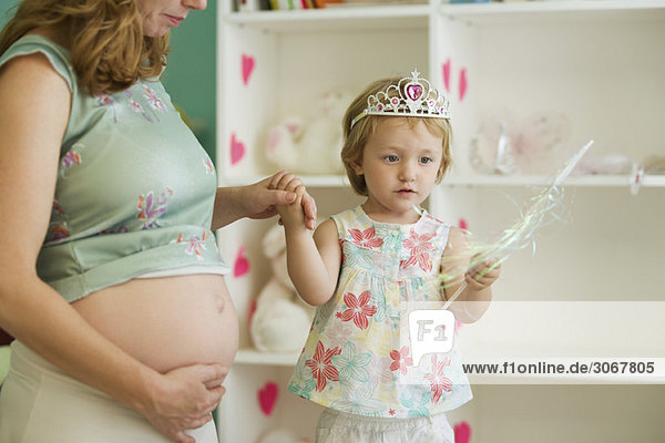 Schwangere Frau spielt mit Tochter im Kinderzimmer