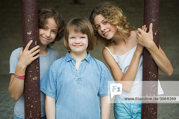 Drei Mädchen stehen nebeneinander  eine mit Down-Syndrom  alle lächelnd vor der Kamera  Porträt