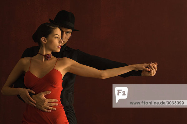 Paar Tango tanzen zusammen  Hände halten  Arme ausgestreckt  Mann schaut in die Kamera