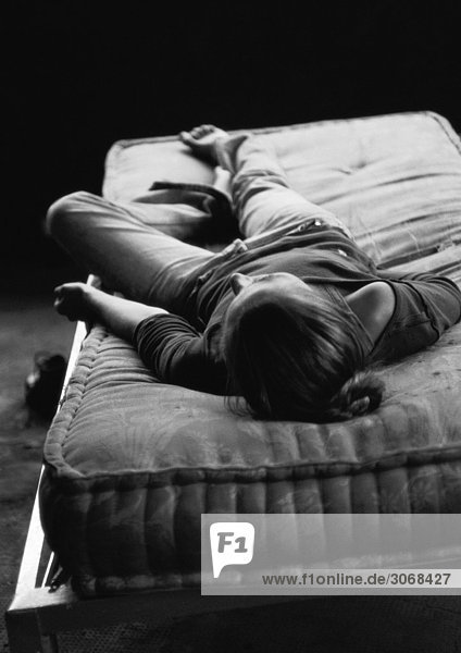 Frau auf dem Rücken liegend auf nackter Matratze