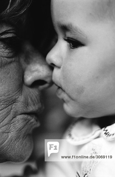 Baby küsst die Nase einer älteren Frau  Seitenansicht