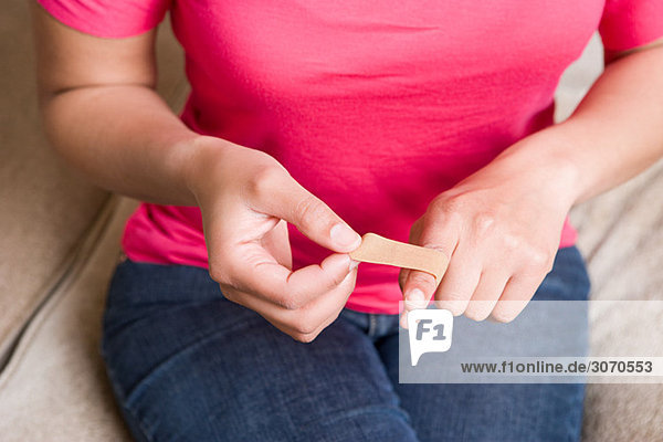 Woman putting plaster on finger