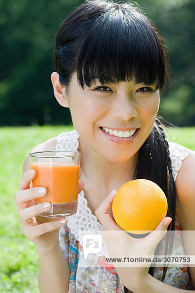 Junge Frau mit einem Glas Saft und Orange