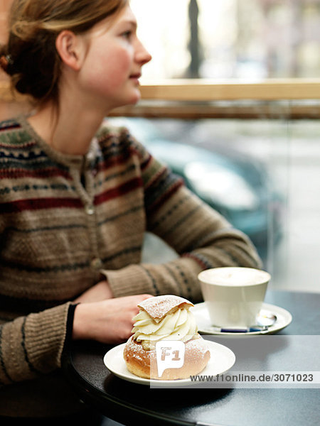 Junge Frau ein Stück Gebäck in einem Café Schweden Essen.
