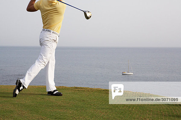 A man playing golf by the sea Gran Canaria Spain.