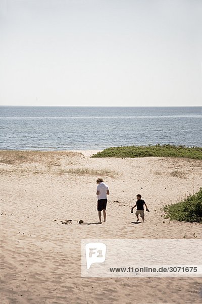 Ein junger Mann und ein Junge Wandern am Strand Schweden.