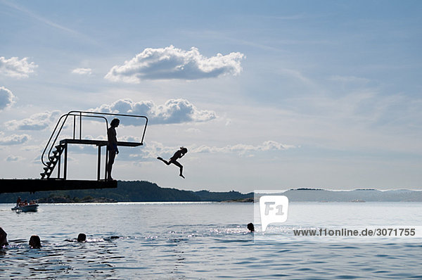 The silhouette of people bathing by a diving tower Sweden.