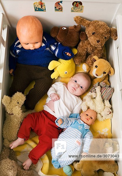 Ein Baby in einem Bett mit kuscheligen Spielzeug und Puppen Schweden