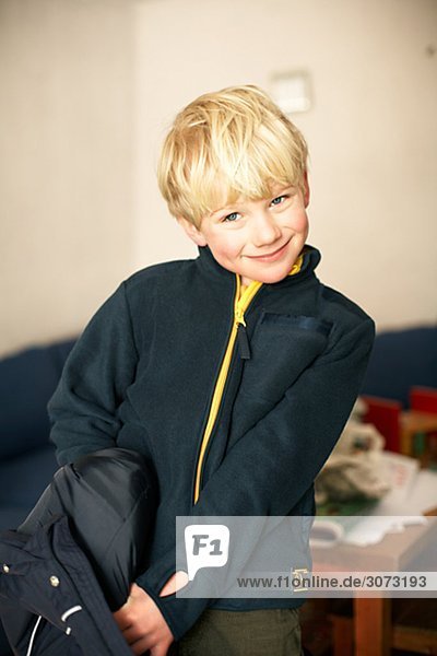 A smiling boy taking his jacket off Sweden.